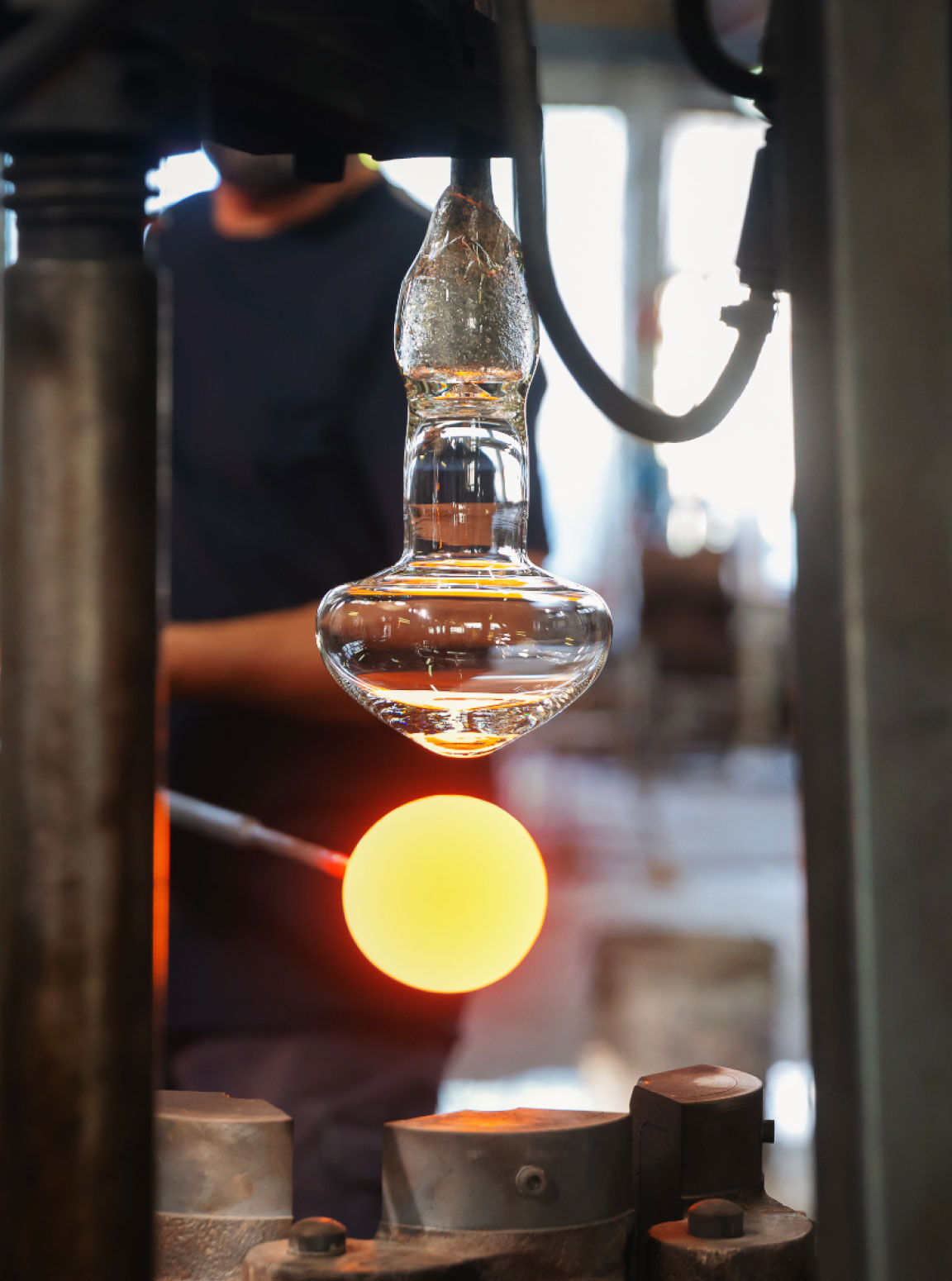 Glassblower gathering molten glass from the crucible